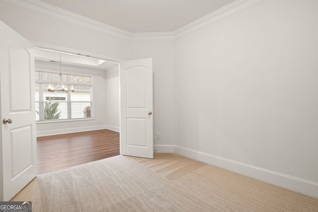 empty room featuring a chandelier, hardwood / wood-style flooring, and ornamental molding