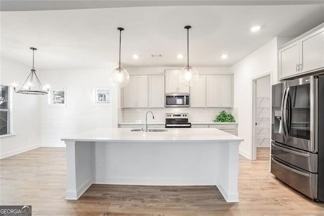 kitchen with white cabinetry, a kitchen island with sink, sink, and appliances with stainless steel finishes