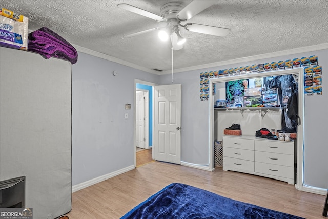 bedroom with ceiling fan, crown molding, light hardwood / wood-style floors, and a textured ceiling