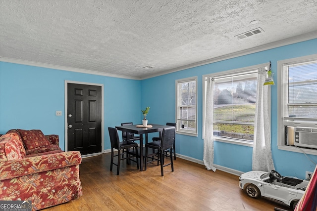 dining area featuring wood-type flooring, a textured ceiling, and ornamental molding