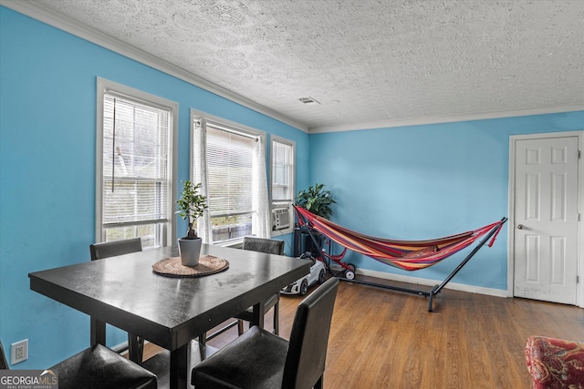 dining area featuring hardwood / wood-style floors, a healthy amount of sunlight, ornamental molding, and a textured ceiling