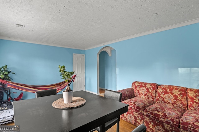 dining room featuring hardwood / wood-style floors, ornamental molding, and a textured ceiling