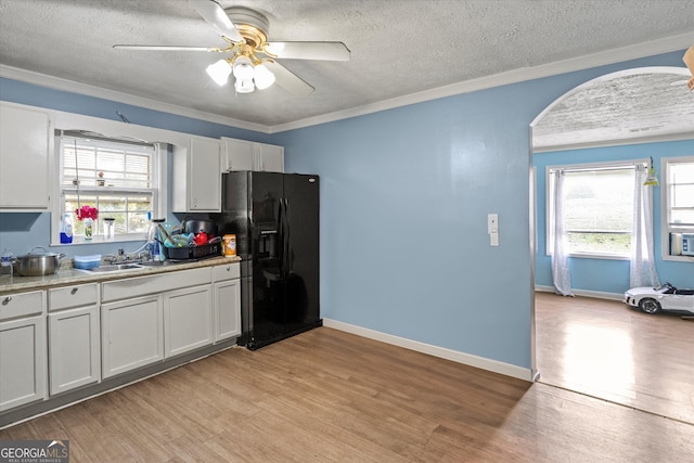 kitchen with black fridge with ice dispenser, a textured ceiling, sink, light hardwood / wood-style flooring, and white cabinets