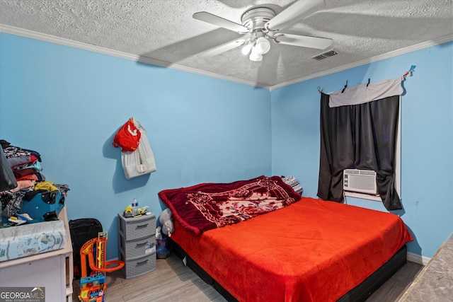 bedroom featuring ceiling fan, cooling unit, a textured ceiling, hardwood / wood-style flooring, and ornamental molding