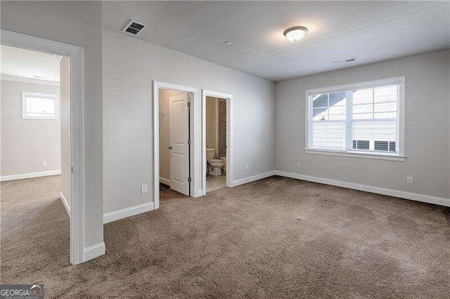 unfurnished bedroom with ensuite bath, carpet floors, and multiple windows