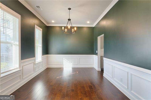 unfurnished dining area with a chandelier, a wealth of natural light, crown molding, and dark wood-type flooring