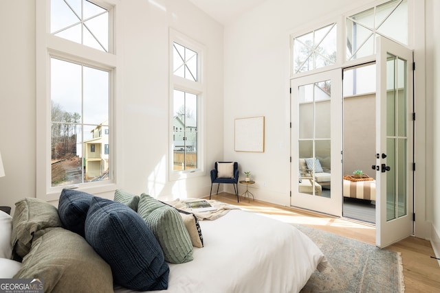 bedroom with light hardwood / wood-style floors and a high ceiling