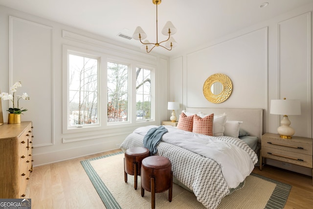 bedroom featuring an inviting chandelier and light wood-type flooring