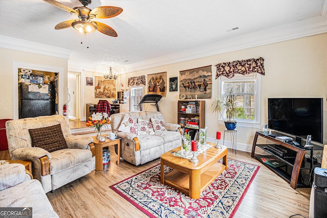 living room with ceiling fan with notable chandelier, wood-type flooring, ornamental molding, and a textured ceiling