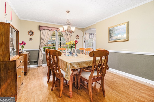 dining room with ornamental molding, a chandelier, a textured ceiling, and light hardwood / wood-style floors