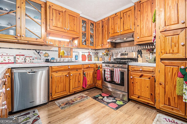 kitchen with sink, tasteful backsplash, light hardwood / wood-style flooring, tile counters, and stainless steel appliances