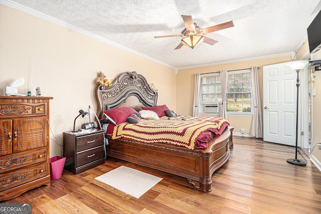 bedroom with crown molding, ceiling fan, cooling unit, a textured ceiling, and light wood-type flooring