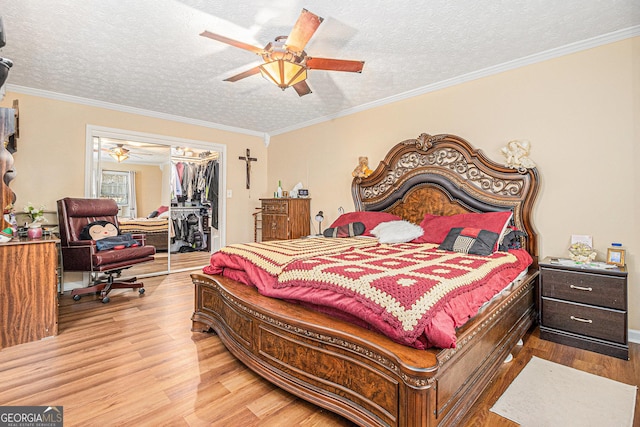 bedroom featuring hardwood / wood-style flooring, ornamental molding, a textured ceiling, a walk in closet, and a closet