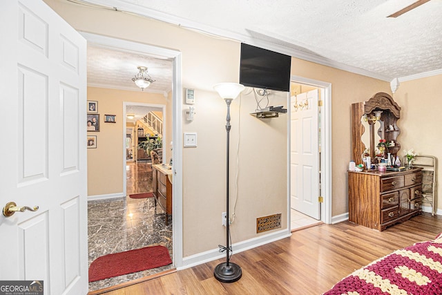 bedroom with crown molding, wood-type flooring, and a textured ceiling