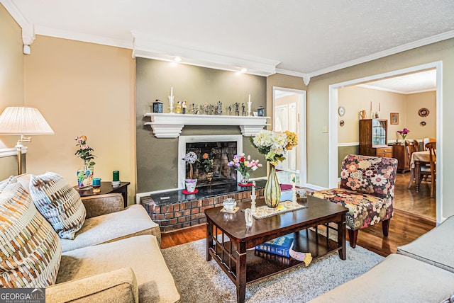 living room featuring hardwood / wood-style floors, ornamental molding, and a brick fireplace