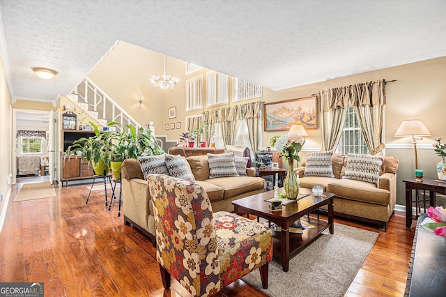 living room featuring hardwood / wood-style flooring, plenty of natural light, a textured ceiling, and an inviting chandelier