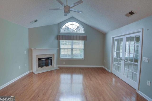 unfurnished living room featuring a high end fireplace, light hardwood / wood-style flooring, ceiling fan, and lofted ceiling