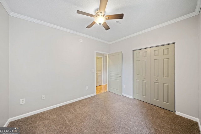 unfurnished bedroom featuring carpet flooring, a textured ceiling, ceiling fan, crown molding, and a closet