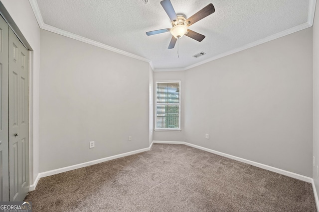 carpeted empty room featuring ceiling fan, crown molding, and a textured ceiling