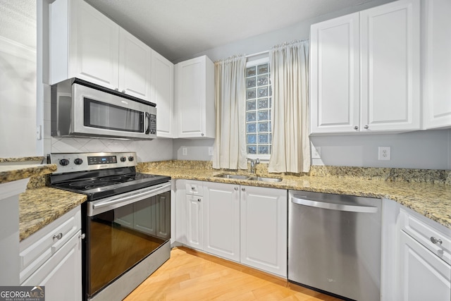 kitchen featuring white cabinetry, sink, stainless steel appliances, and light wood-type flooring