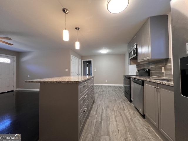 kitchen featuring stainless steel appliances, pendant lighting, wood-type flooring, gray cabinets, and a kitchen island