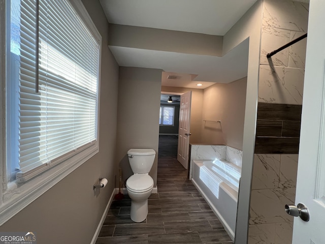 bathroom with ceiling fan, toilet, and a tub