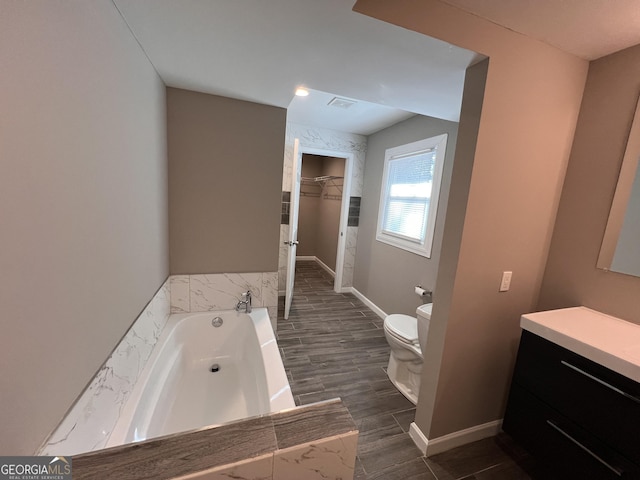 bathroom with a washtub, hardwood / wood-style floors, vanity, and toilet