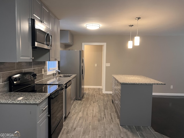 kitchen featuring stainless steel appliances, light hardwood / wood-style flooring, hanging light fixtures, and gray cabinetry