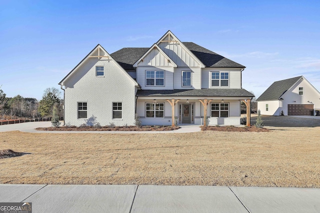 view of front of home with a porch, a front yard, an outdoor structure, and a garage