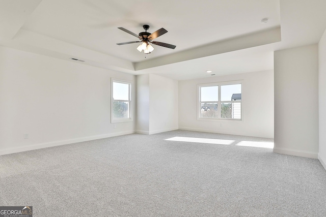 spare room featuring a tray ceiling, ceiling fan, and light colored carpet