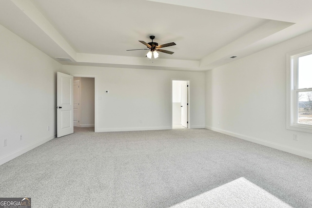 unfurnished room featuring carpet flooring, ceiling fan, and a raised ceiling