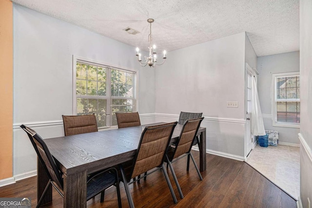 dining room featuring a notable chandelier, dark wood-type flooring, and a textured ceiling