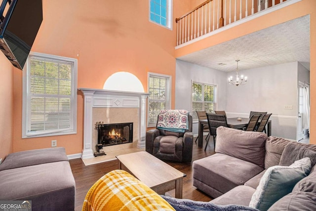 living room with a textured ceiling, a towering ceiling, a notable chandelier, and hardwood / wood-style flooring