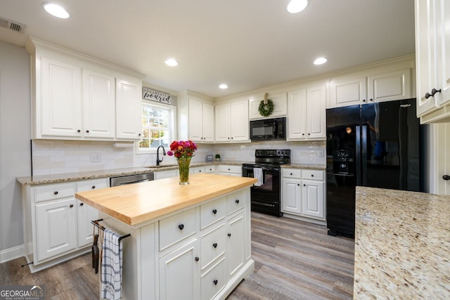 kitchen featuring a center island, white cabinetry, butcher block counters, and black appliances