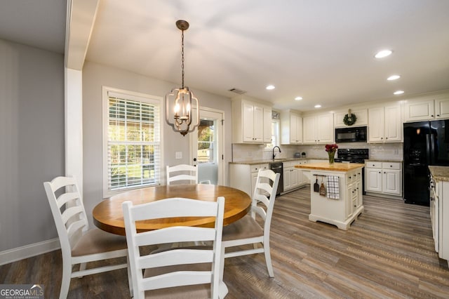 kitchen with white cabinetry, a center island, dark hardwood / wood-style flooring, backsplash, and black appliances