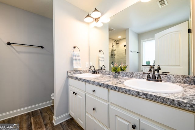 bathroom featuring hardwood / wood-style flooring, vanity, toilet, and a tile shower