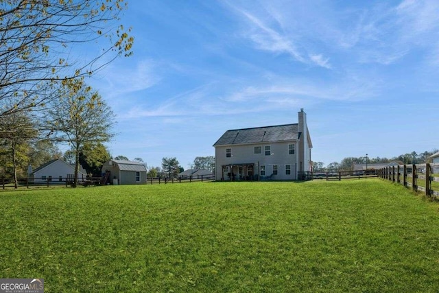 rear view of house with a lawn and a shed