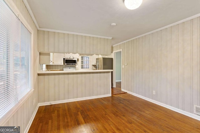 kitchen with kitchen peninsula, hardwood / wood-style floors, stainless steel appliances, and crown molding