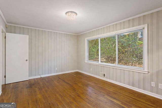 empty room with hardwood / wood-style flooring and ornamental molding