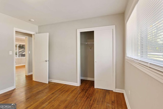 unfurnished bedroom featuring a closet and dark wood-type flooring