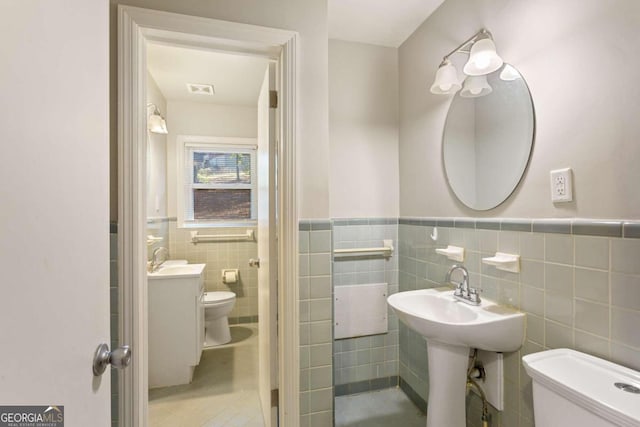 bathroom featuring tile patterned flooring, tile walls, and toilet