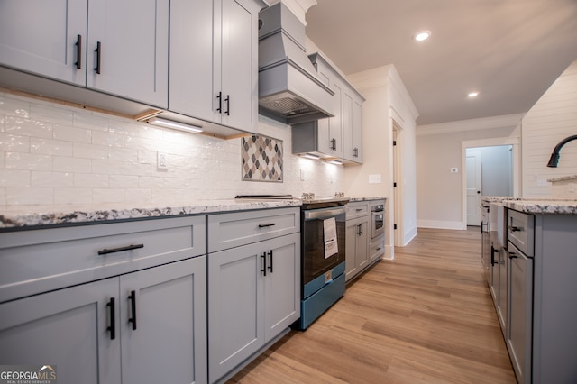 kitchen with light stone countertops, premium range hood, ornamental molding, light hardwood / wood-style floors, and gray cabinets