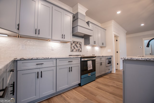 kitchen featuring stainless steel appliances, crown molding, gray cabinets, custom exhaust hood, and light wood-type flooring