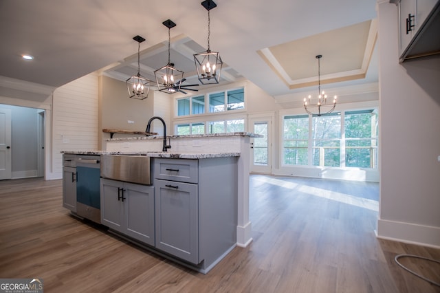 kitchen with light wood-type flooring, a tray ceiling, decorative light fixtures, dishwasher, and gray cabinets