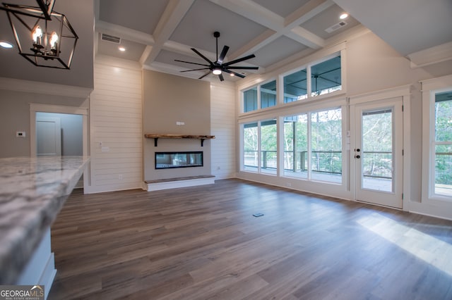 unfurnished living room with beamed ceiling, ceiling fan with notable chandelier, dark hardwood / wood-style floors, and coffered ceiling