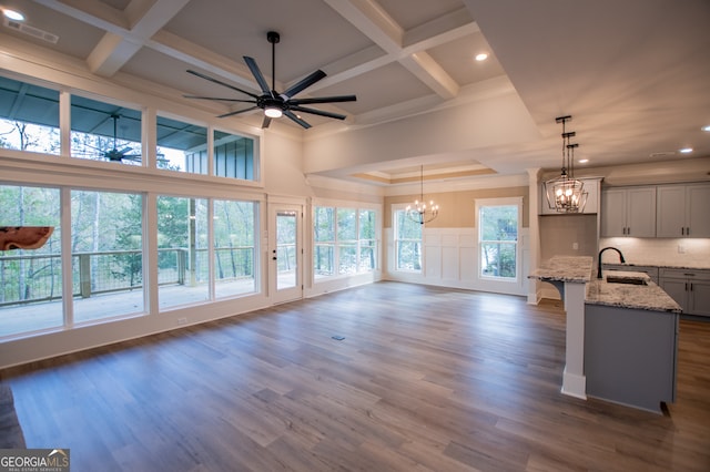 kitchen with light stone counters, sink, pendant lighting, gray cabinets, and dark hardwood / wood-style floors