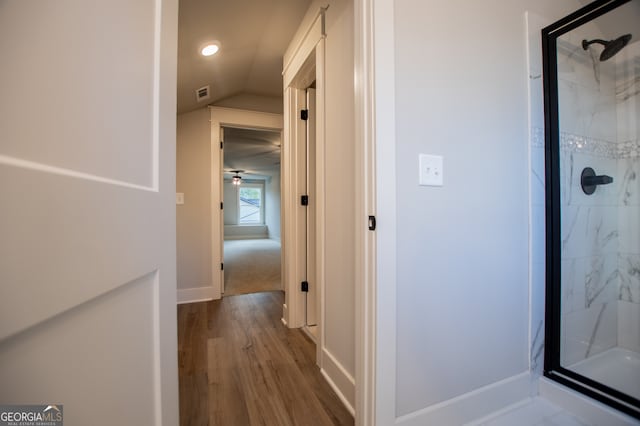 hallway with wood-type flooring and lofted ceiling