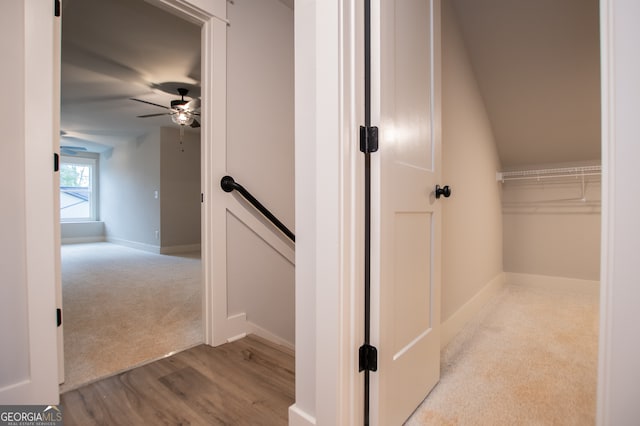 stairs with ceiling fan, lofted ceiling, and hardwood / wood-style flooring