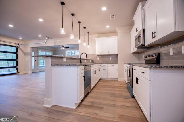 kitchen featuring backsplash, white cabinets, light wood-type flooring, and appliances with stainless steel finishes