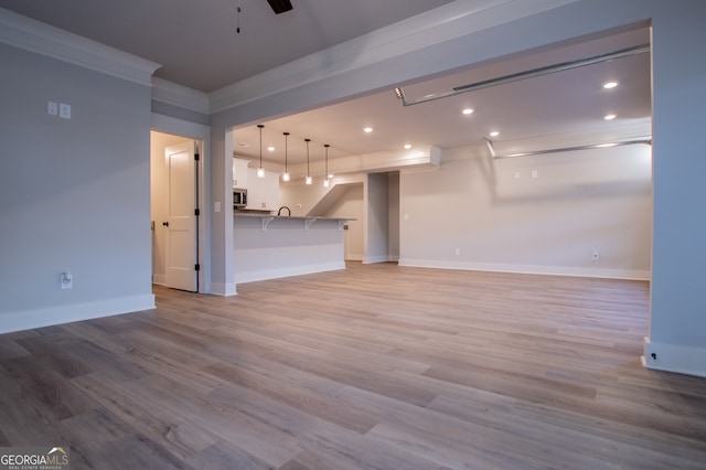 unfurnished living room with light wood-type flooring, ceiling fan, and crown molding